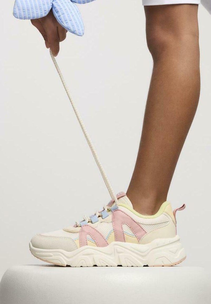 Baskets multicolores avec une palette pastel, en mesh et matériau synthétique, semelle blanche épaisse et accents en zigzag distincts.