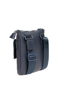 Kompaktní tmavě modrá kožená crossbody taška s texturovaným povrchem, zipovým uzávěrem a nastavitelným popruhem se zdobením loga.