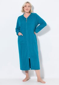 Accappatoio teal con zip, maniche lunghe, due tasche frontali e lunghezza fino a metà polpaccio. Texture morbida e vestibilità comoda. Dotato di chiusura con zip frontale.