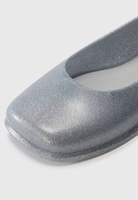 Ballet flat en argent pailleté avec un bout arrondi et un design découpé. Surface texturée apportant de l'éclat, avec une doublure intérieure lisse.