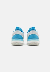 Zapatillas deportivas azules y blancas con parte superior de malla, cuello acolchado y suela de goma con un patrón de agarre texturizado.