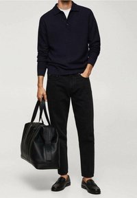 Marineblauer Strick-Polo-Pullover, schwarze Jeans, schwarze Lederhandtasche mit doppelten Griffen und schwarze Slipper. Einfaches, körpernahes Design ohne Muster.