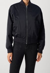 Černá bomber bunda vyrobená z hladké tkaniny, s předním zipem, žebrovanými manžetami a spodním lemem a bočními kapsami pro funkčnost.