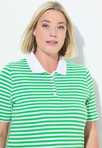 Polo a righe verde e bianche con colletto bianco, realizzato in tessuto liscio, dotato di una lista di bottoni e maniche corte.