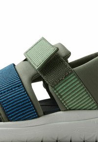 Gröna och blå sandaler med textilöverdel, som har kardborreknäppningar och en strukturerad vit gummisula.