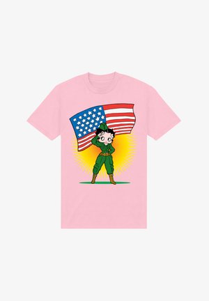 Růžové tričko se zabavným charakterem v zeleném vojenském oblečení, jak salutuje, s americkou vlajkou v ruce, na pozadí žlutého slunečního paprsku.