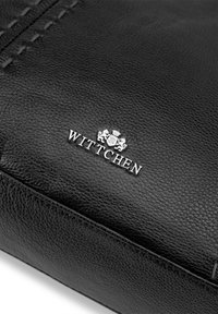 Portafoglio in pelle nera con texture visibile, dettagli cuciti e un logo argento "WITTCHEN" con accenti decorativi.