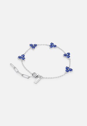 Pulsera de plata con cinco grupos de tres gemas ovaladas azules distribuidas uniformemente en una cadena fina y un cierre de langosta con eslabones de extensión.
