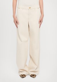 Beige wide-leg trousers with a button closure and front pockets. Fabric appears smooth with a slight texture, paired with leopard print shoes.
