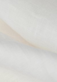 Skiktade tyger i olika nyanser av vitt och kräm, som visar en slät, vävd textur med ett lätt och luftigt utseende.