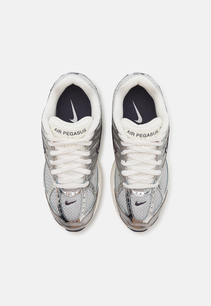 Las zapatillas Nike Air Pegasus presentan un upper de malla y sintético en color plateado, cordones blancos, una plantilla en azul marino y un detalle del swoosh reflectante.