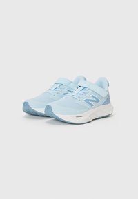 Baskets de sport bleu clair avec tige en maille, accents blancs, sangle réglable et semelle rembourrée conçue pour le confort et le soutien.