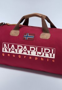 Borsa da viaggio bordeaux con base in suede marrone, dotata di una patch della bandiera norvegese e di un audace marchio "NAPAPIJRI" in bianco. Forma rettangolare, manici robusti.