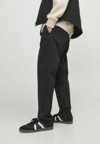 Sorte tapered bukser lavet af glat stof, med sidelommer og en afslappet pasform. Stylet med sorte sneakers med hvide striber.