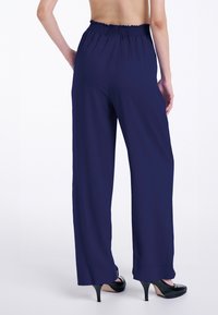 Pantaloni a gamba larga blu navy con cintura arricciata. Realizzati in materiale morbido, presentano un drappeggio fluido e un orlo alla caviglia.