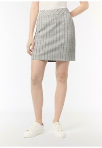 Szara, dopasowana mini spódnica z teksturowanej tkaniny, z motywem w kratkę. Noszona z gładkimi białymi sneakersami.