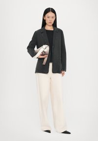 Blazer di jeans neri, camicia nera fitted, pantaloni larghi crema e una borsa piccola con una tracolla chiara. Scarpe nere a punta, design semplice.