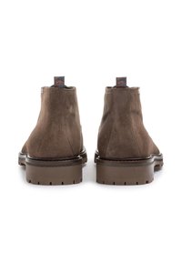 Botas de tobillo de ante marrón con un acabado texturizado, punta redondeada, suela resistente y tira de agarre con diseño en el talón.