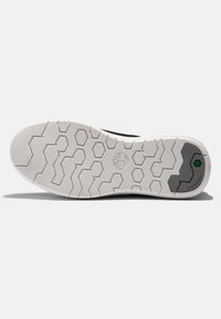 Black athletic shoe with a textured white rubber outsole featuring hexagonal patterns and a gray accent on the side.