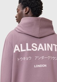 Felpa viola realizzata in morbido tessuto, con grande scritta bianca "ALLSAINTS", caratteri giapponesi e "LONDON" in basso.