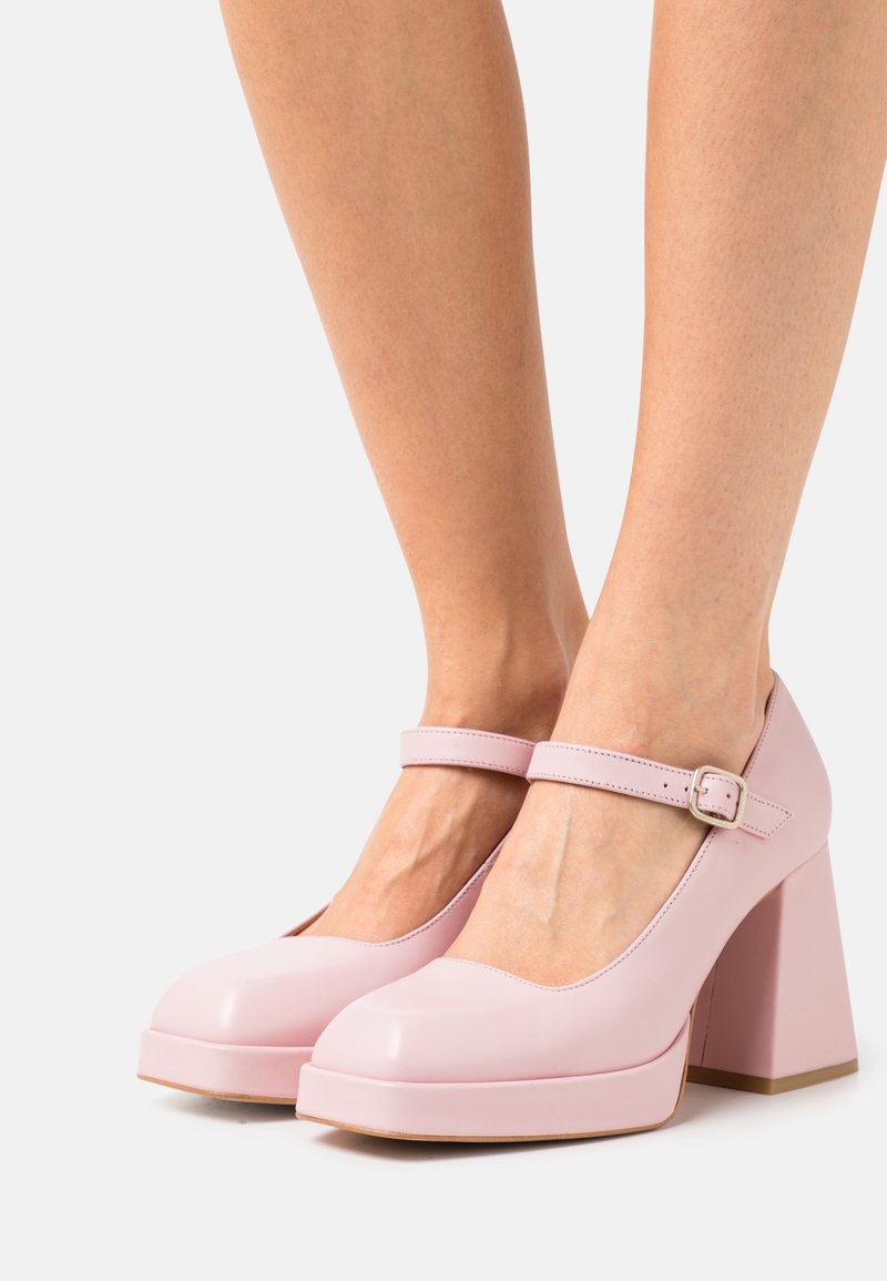 Roze lakleren Mary Jane-hakken met een ronde neus, verstelbare enkelriem en een stevige, vierkante hak. Glad oppervlak en effen kleur.