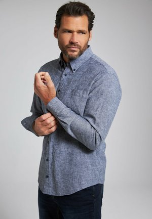 Blauwe gestructureerde overhemd met lange mouwen, een zak en donkere knopen, gedragen met een marineblauwe spijkerbroek. Het overhemd heeft een casual pasvorm.