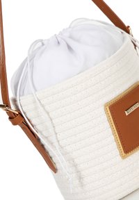 Borsa a secchiello rotonda realizzata in tessuto bianco testurizzato, con chiusura a coulisse e tracolla in pelle marrone. Presenta una patch con logo.