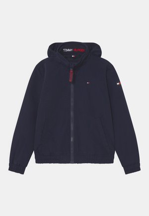 Veste à capuche bleu marine Tommy Hilfiger avec poignets élastiques, fermeture éclair à l'avant, deux poches et écussons logo sur la poitrine, la manche et l'intérieur du col.