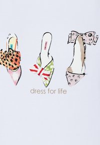 Tres zapatos de punta con lazo: estampado de leopardo con cuentas negras, verde con rayas rojas y blancas, rosa con tachuelas plateadas, sobre el texto "vístete para la vida".