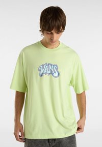 Camisa de manga corta verde lima de algodón, con un logotipo gráfico central en azul y blanco. Corte relajado con cuello redondo.