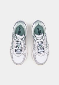 Baskets blanches et gris clair avec un dessus en mesh, des lacets ronds et un col rembourré. Présente des accents verts et une semelle texturée.