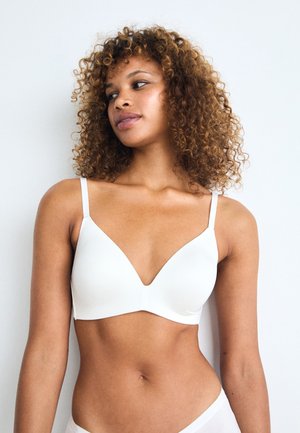 White wireless bra with a deep V-neckline, adjustable thin straps, and smooth fabric. Simple design without padding or decoration.