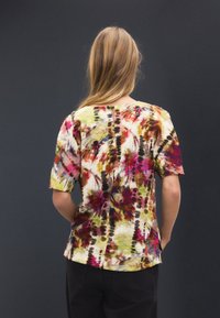 Košeľa s krátkym rukávom s farebným vzorom tie-dye v odtieňoch ružovej, zelenej a žltej, s rovnou švíkovou zadnou časťou a voľným strihom.