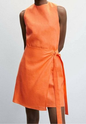 Ærmeløs, lys orange slå-om-kjole med en knude i siden, båret af en mørkhudede person mod en ensfarvet lys baggrund.