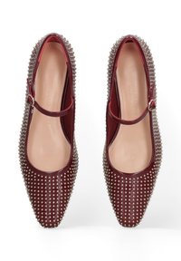 Ballerines Mary Jane en cuir bordeaux avec un bout pointu, ornées de clous en argent le long des bords et d'une sangle à boucle. Intérieur lisse.