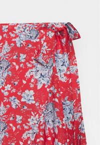 Tela roja con un patrón floral azul y blanco, con detalle de un lazo atado a un lado.