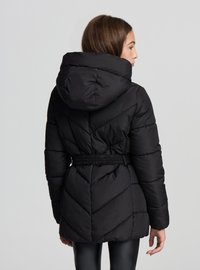 Czarna pikowana kurtka z kapturem, z paskiem w talii oraz geometrycznym wzorem pikowania na plecach i bokach.