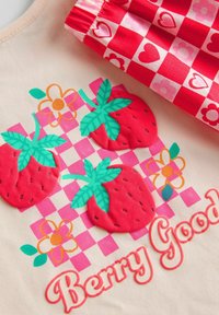Lys beige stof prydet med tre teksturerede røde jordbær med grønne blade, detaljer i gult og grønt blomster, og "Berry Good" i pink tekst.