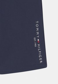 Granatowe szorty z miękkiego materiału, z haftowanym napisem "TOMMY HILFIGER" i detalem logo na lewym nogawicy.