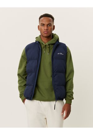 Dunkelblauer Puffer-Westen mit Reißverschluss, gestepptem Design und hohem Kragen, getragen über einem grünen Hoodie mit Kordelzug. Strukturiert Stoff.
