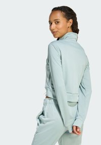 Light blue athletic tracksuit featuring a zip-up jacket with a high collar and matching relaxed-fit pants with elastic waistband and pockets.