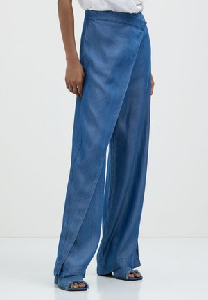 Pantalons en denim bleu à jambes larges avec une texture lisse et un design enroulé. Caractéristiques d'une taille haute et tombent librement jusqu'au sol.