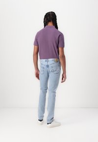 Short-sleeve purple polo shirt, light blue slim-fit jeans, and white sneakers. Made of cotton blend with a smooth texture.