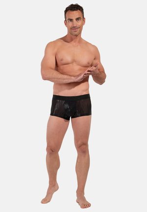 Mustat, paljetein koristellut uimashortsit, joissa on vartalonmyötäinen malli ja joustava vyötärönauha. Kangas heijastaa valoa korostaen kiiltävää pintaa.