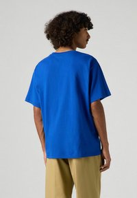 Camiseta de algodón azul con cuello redondo y mangas cortas, que presenta un ajuste relajado y una textura suave. Mostrada desde la parte de atrás.