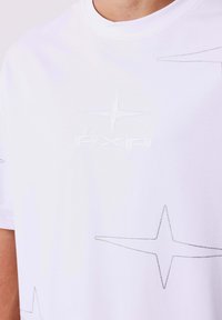 Witte katoenen t-shirt met korte mouwen, featuring een tonale geborduurde "PXP"-logo en stippen sterpatronen op de stof, met een gladde textuur.