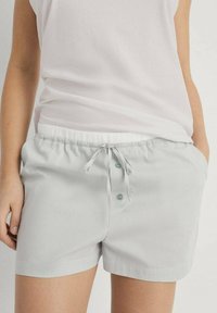 Lichtgrijze gestreepte shorts met een elastische tailleband, trekkoordsluiting en twee knopen aan de voorkant, gemaakt van een zachte stof.