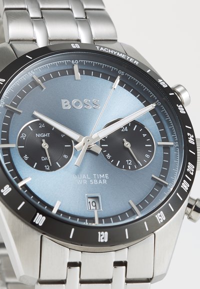 Montre en acier inoxydable argenté avec un cadran dégradé bleu, des indicateurs de temps double, une échelle tachymétrique et un affichage de la date à 16 heures.