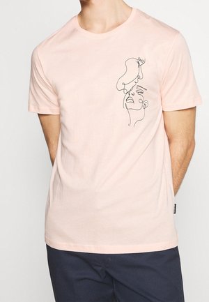 Koszulka z krótkim rękawem w jasnoróżowym kolorze, wykonana z bawełny, z czarnym rysunkiem przedstawiającym twarze na przodzie, z okrągłym dekoltem i regularnym krojem.