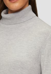 Hellgrauer Rollkragenpullover mit geripptem Halsausschnitt und glatter Textur, der eine Nahaufnahme des Stoffs und der Nähdetails zeigt.